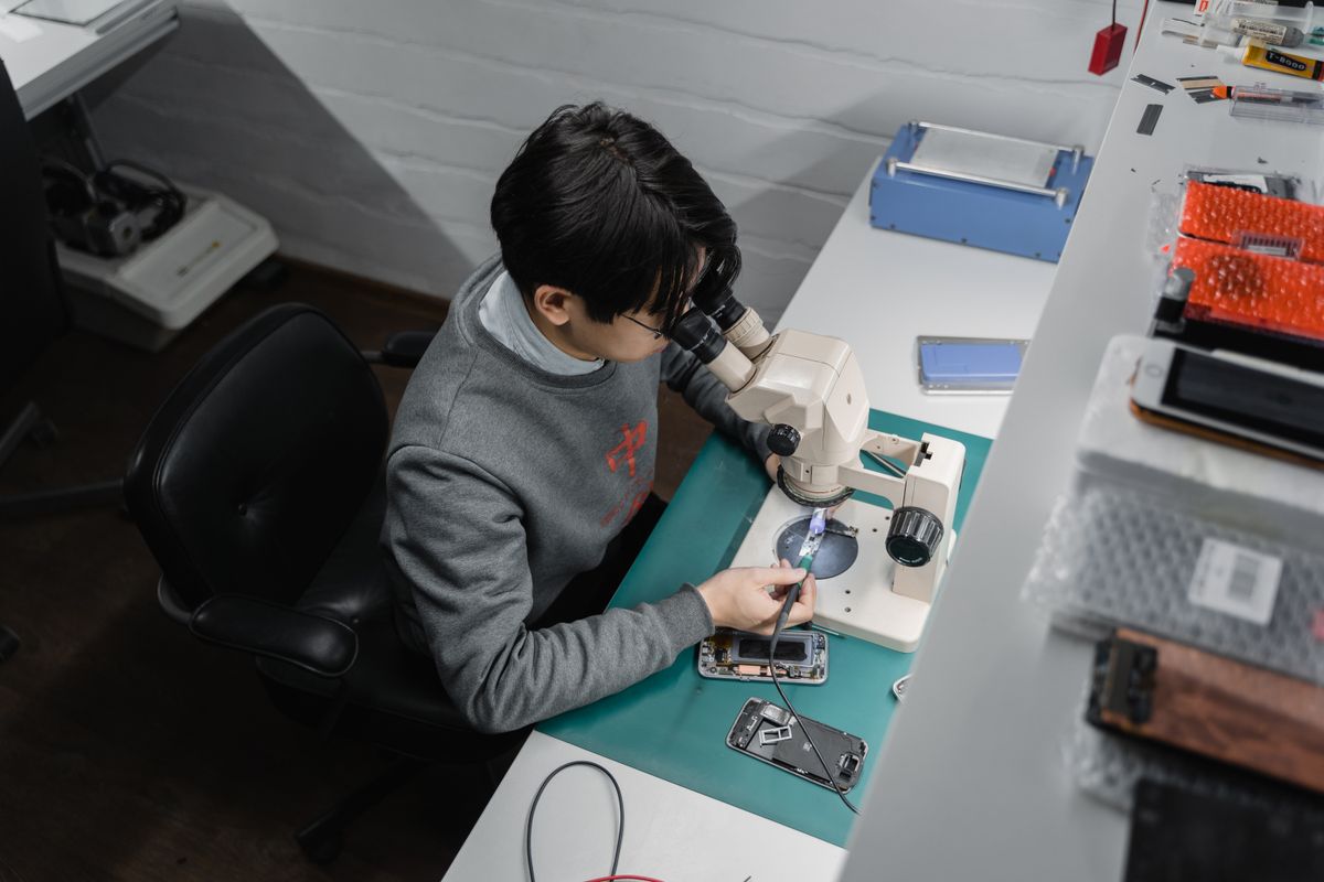 Smartphone repair workbench with technician and microscope